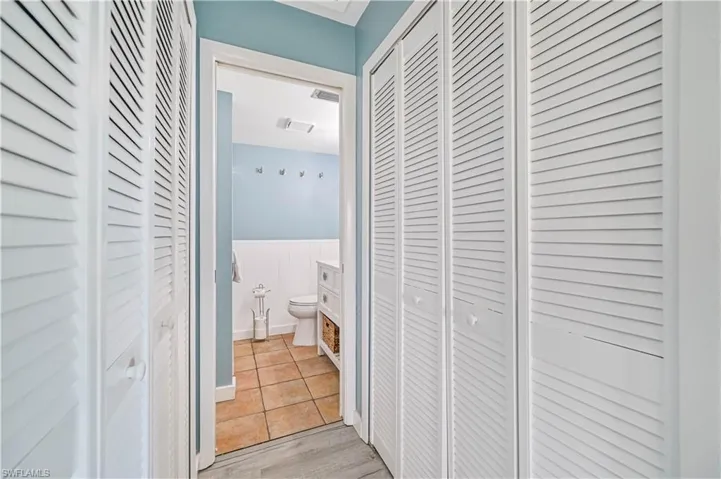 Corridor featuring light tile patterned floors, wainscoting, and visible vents