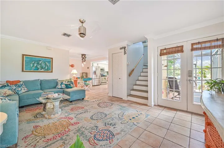 Living room featuring french doors, crown molding, stairway, and tile patterned floors