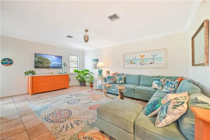 Living area featuring visible vents, crown molding, baseboards, and light tile patterned flooring