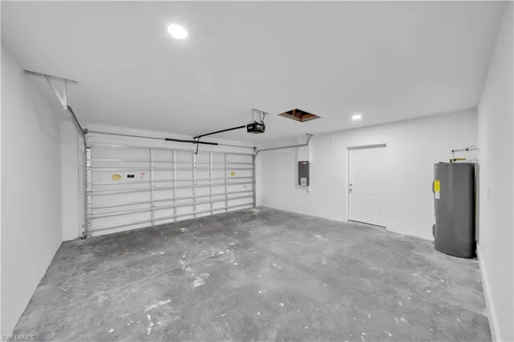 Spacious garage with a concrete floor, overhead lighting, and an automatic garage door opener