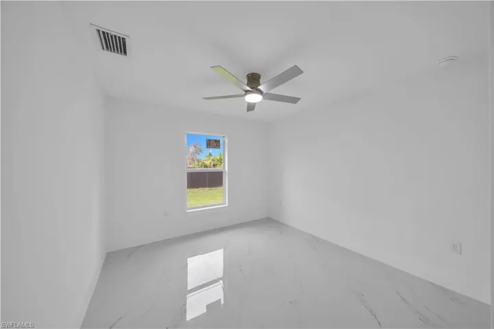 Bright interior with white walls, a single window, a ceiling fan, and large format tile flooring