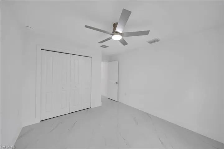 Contemporary ceiling fan with integrated lighting, bi-fold closet doors, sleek tile flooring, and clean white walls