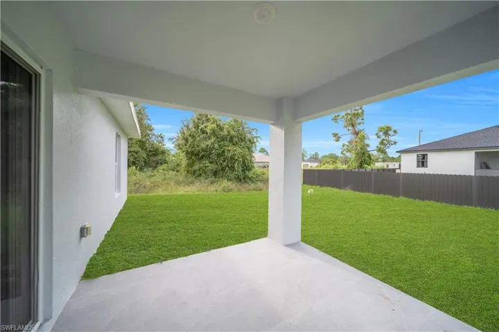 Covered patio with tile flooring, recessed lighting, and a spacious grassy area