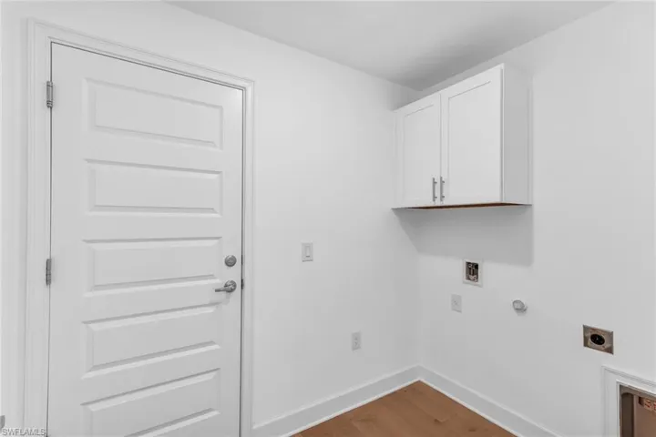 Laundry room with upper cabinet for storage. Door leading to the garage.