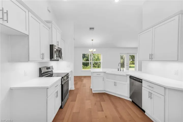 View of the kitchen looking into the dining area.  Under cabinet lighting, stainless steel appliances.
