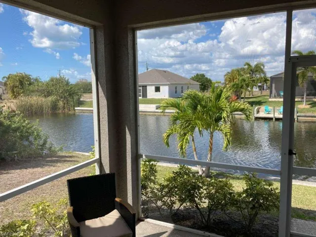 Enjoy scenic views of the waterway and surrounding landscape, featuring palm trees and lush greenery, from the comfort of this screened outdoor area