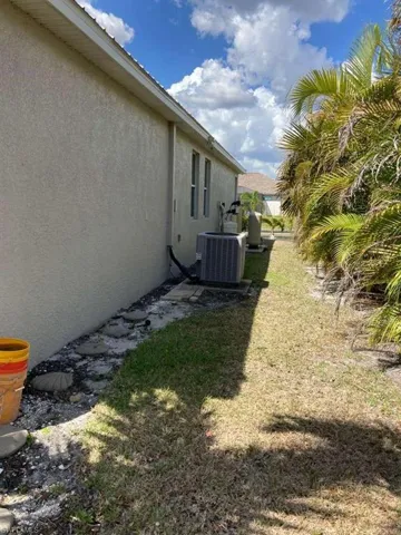 The property features a stucco exterior, a well-maintained lawn, and established palm trees