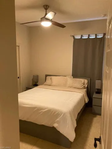 Bedroom featuring a ceiling fan with integrated lighting, tile flooring, and light-colored walls