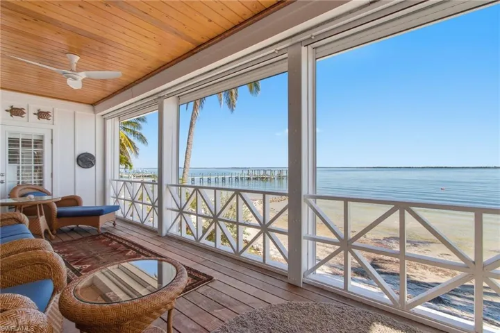 Sunroom with view of water and beach, wood ceiling, and hardwood / wood-style flooring