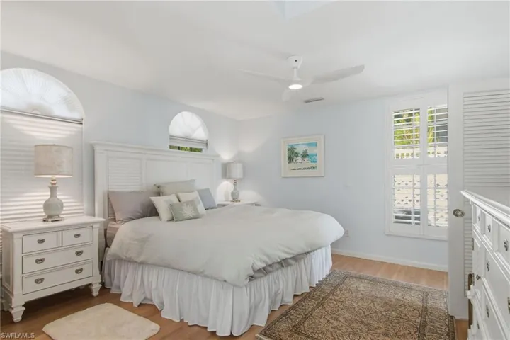 Bedroom with light wood-style flooring, ceiling fan, and multiple windows