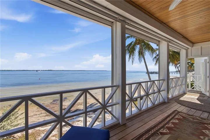 Unfurnished sunroom with view of water and beach, hardwood / wood-style flooring, and wood ceiling