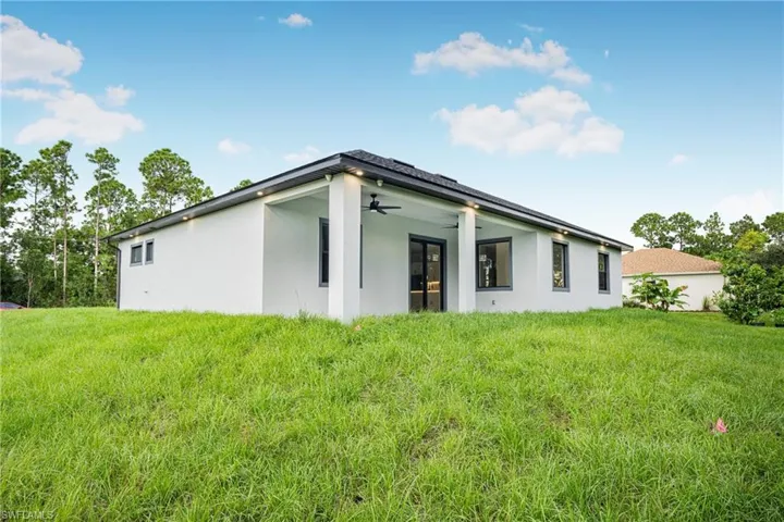 Back of house with a lawn and ceiling fan