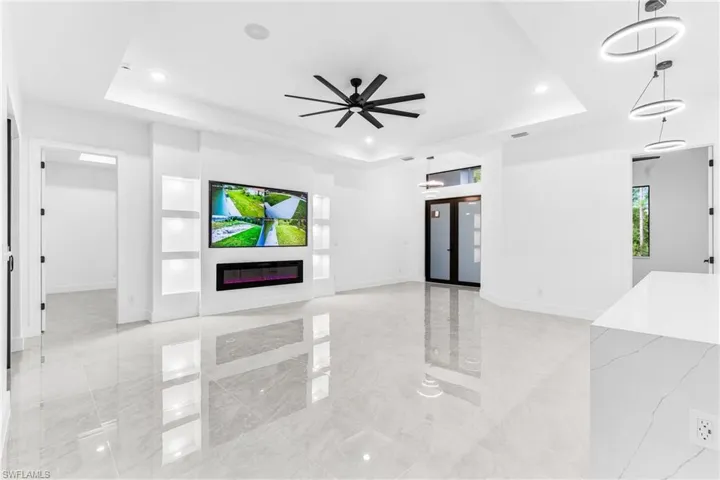 Unfurnished living room featuring ceiling fan and a raised ceiling
