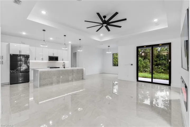 Living room featuring a tray ceiling, sink, and ceiling fan