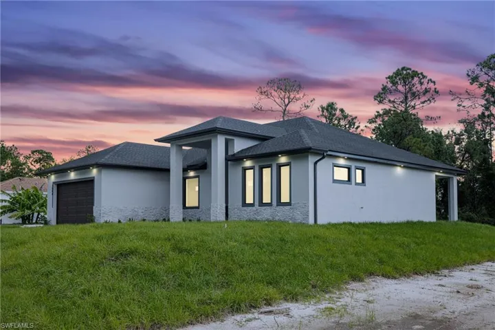 Property exterior at dusk with a yard and a garage