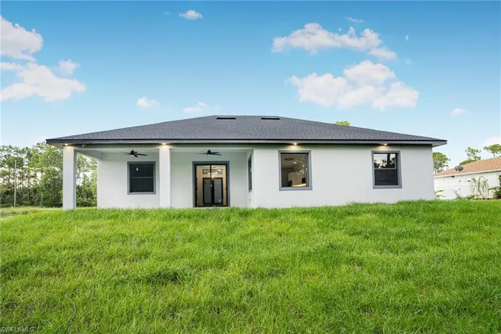Back of house featuring ceiling fan and a yard
