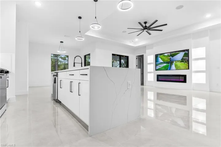 Kitchen with ceiling fan, light stone countertops, hanging light fixtures, and white cabinetry