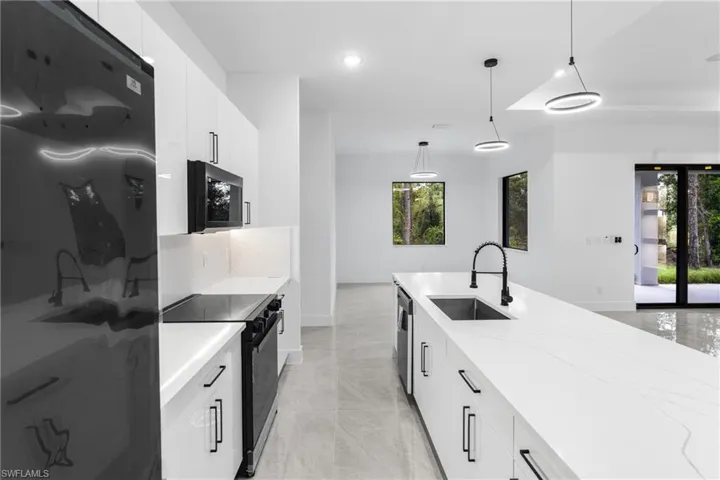 Kitchen featuring white cabinets, appliances with stainless steel finishes, pendant lighting, and sink