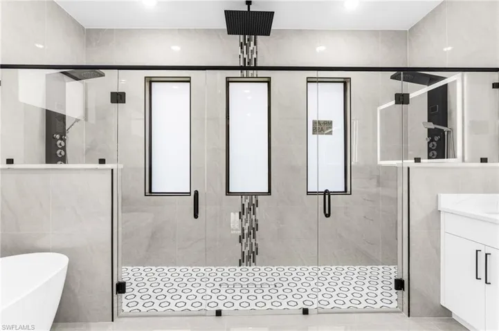 Bathroom featuring tile walls, shower with separate bathtub, tile patterned floors, and vanity