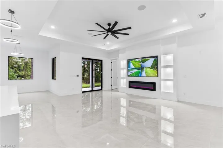 Unfurnished living room with a tray ceiling and ceiling fan