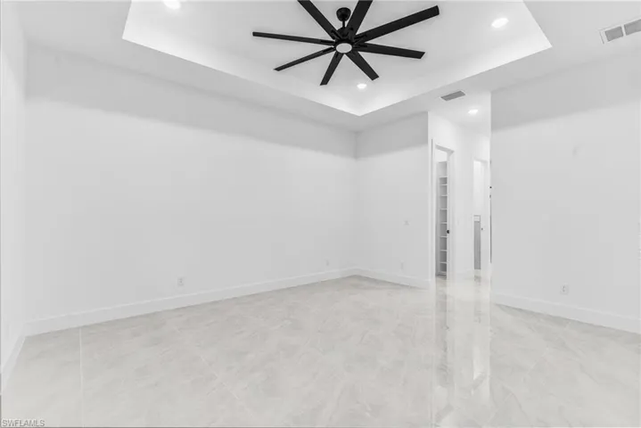 Spare room with a raised ceiling and ceiling fan