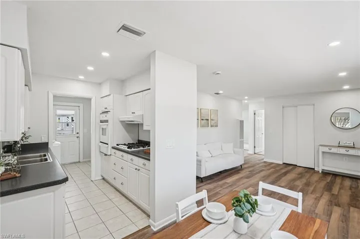 Kitchen with dark countertops, white cabinets, open floor plan, recessed lighting, and light wood-style floors