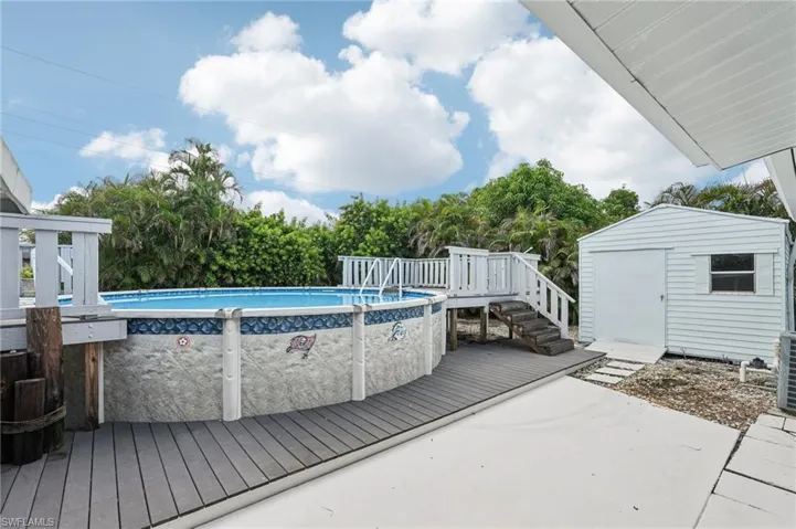 Swimming pool featuring a deck, a storage shed, and view of wooded area