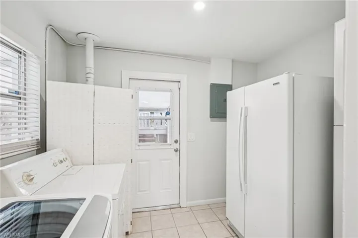 Laundry room with light tile patterned floors, washer and clothes dryer, and electric panel