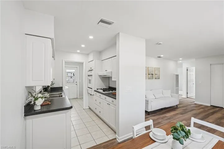 Kitchen with dark countertops, recessed lighting, white cabinetry, open floor plan, and light wood finished floors