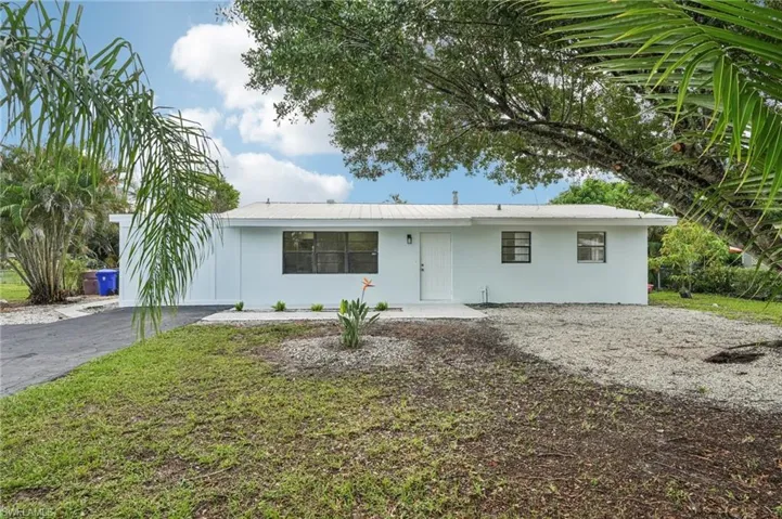 Single story home with driveway, stucco siding, and a front lawn