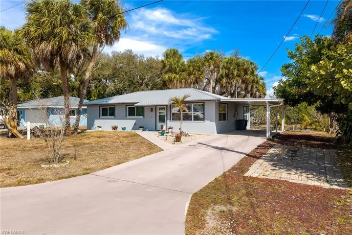 Single story home featuring a carport, concrete driveway, a metal roof, stucco siding, and a front lawn