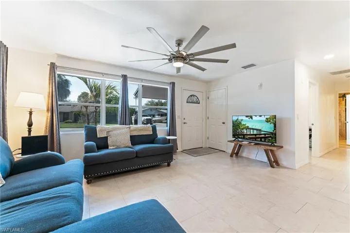Living room with ceiling fan and light tile patterned flooring