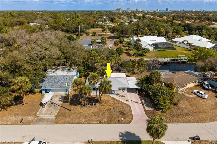 Aerial perspective of suburban area with a nearby body of water and a tree filled landscape
