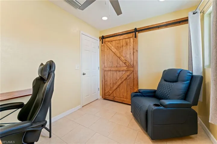 Office with a barn door, ceiling fan, recessed lighting, and light tile patterned flooring