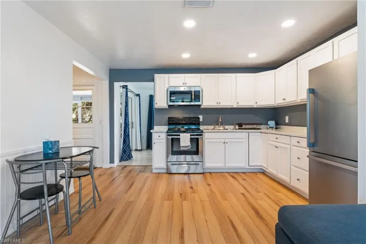 Kitchen with stainless steel appliances, light countertops, light wood-style flooring, white cabinetry, and recessed lighting