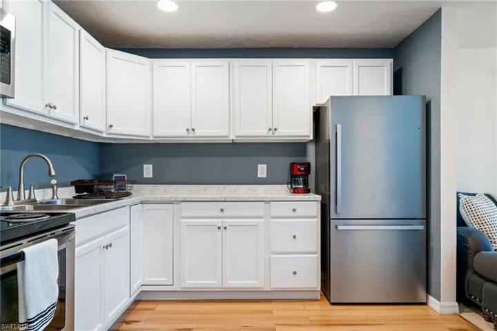 Kitchen with stainless steel appliances, white cabinets, light countertops, light wood-style floors, and recessed lighting