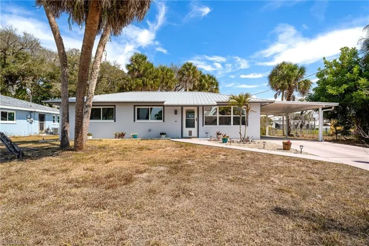 Ranch-style home with a carport, driveway, a front yard, and stucco siding