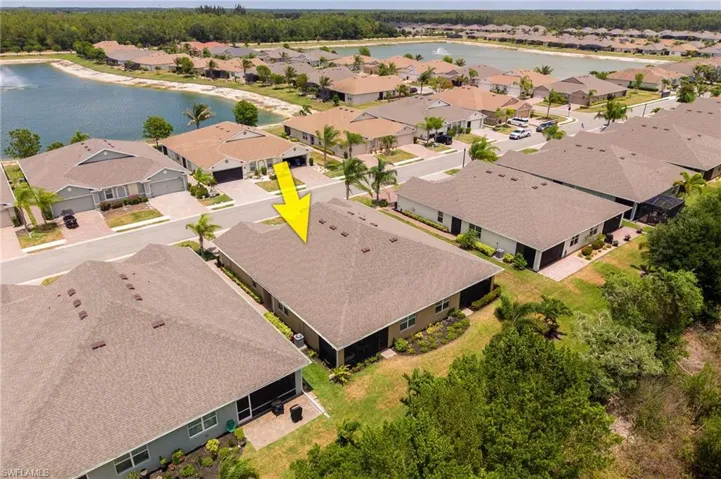 Aerial view of a residential property with a brown shingle roof, a screened-in patio, and a landscaped yard