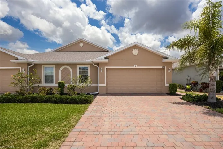 Stucco exterior featuring a neutral color palette, gable rooflines, and a paver driveway