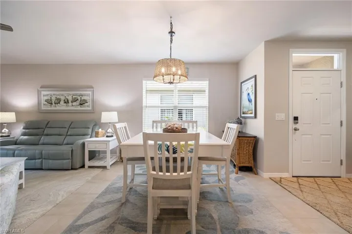 Dining area featuring a woven pendant light fixture, a window with blinds, and tile flooring