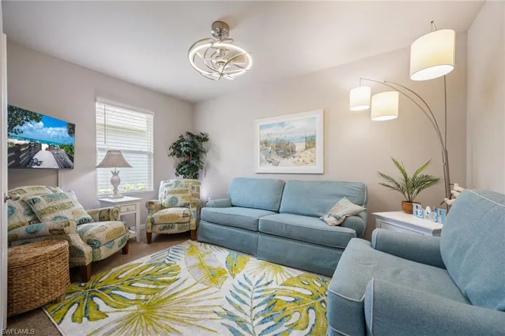 Recessed lighting and a decorative ceiling fixture illuminate this space, featuring light neutral wall tones and a window with blinds