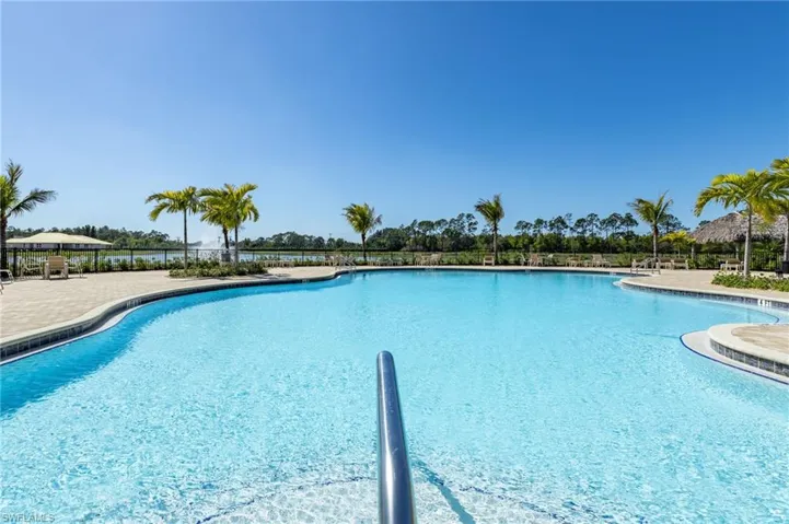 Expansive aquatic amenity featuring a large freeform pool with integrated steps and a metal handrail