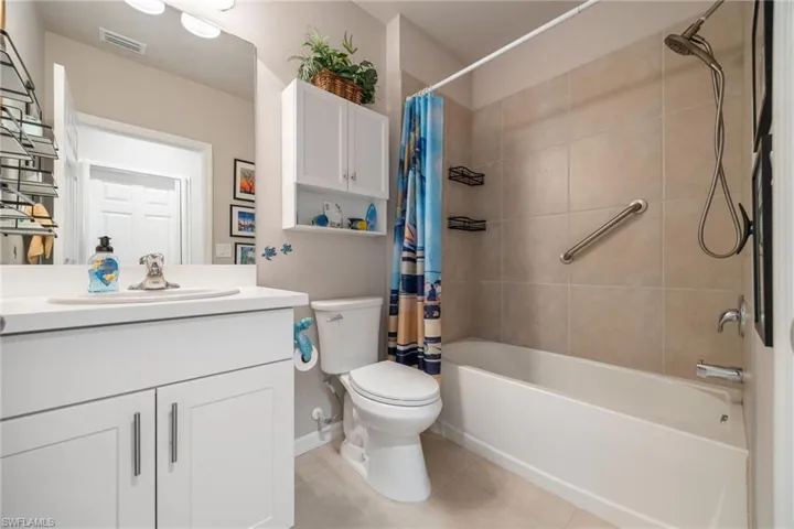 Full bathroom featuring a white vanity with integrated sink, white cabinetry with brushed nickel hardware, and a tub/shower combination
