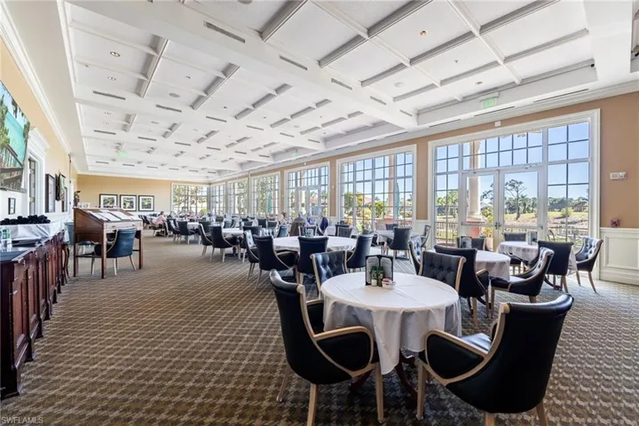 Spacious dining area featuring a coffered ceiling, patterned carpet flooring, and extensive window walls with multiple double-door exits