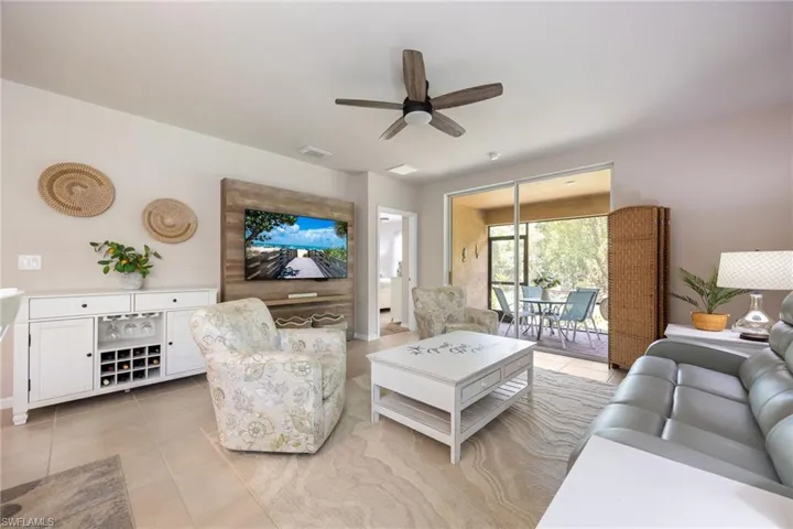 Spacious living area featuring large format tile flooring, a ceiling fan, and a built-in media wall