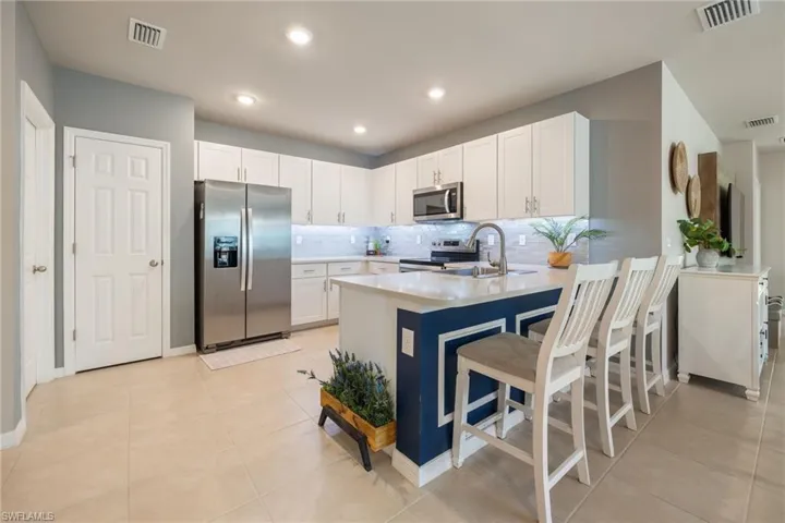 Kitchen featuring white cabinetry, stainless steel appliances, and a central island with a contrasting base and countertop