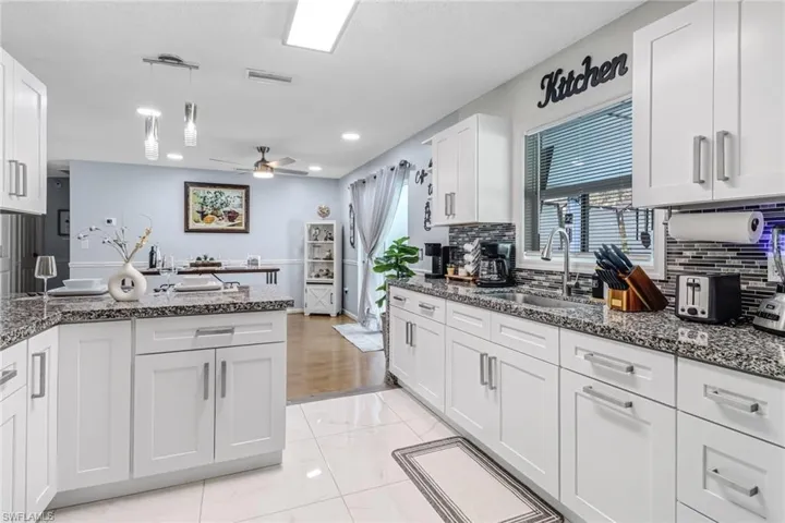 Kitchen featuring a sink, white cabinets, decorative backsplash, ceiling fan, and recessed lighting