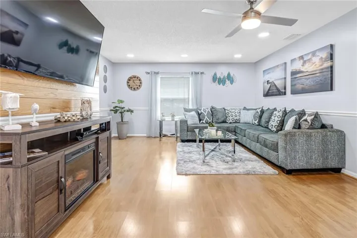 Living area with light wood-style floors, ceiling fan, recessed lighting, a textured ceiling, and baseboards