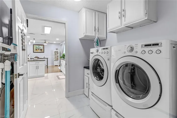 Laundry room with separate washer and dryer, cabinet space, ceiling fan, light marble finish floors, and a textured ceiling