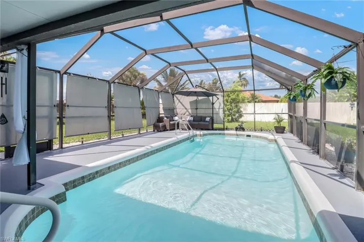 View of pool with glass enclosure, fence, and a patio